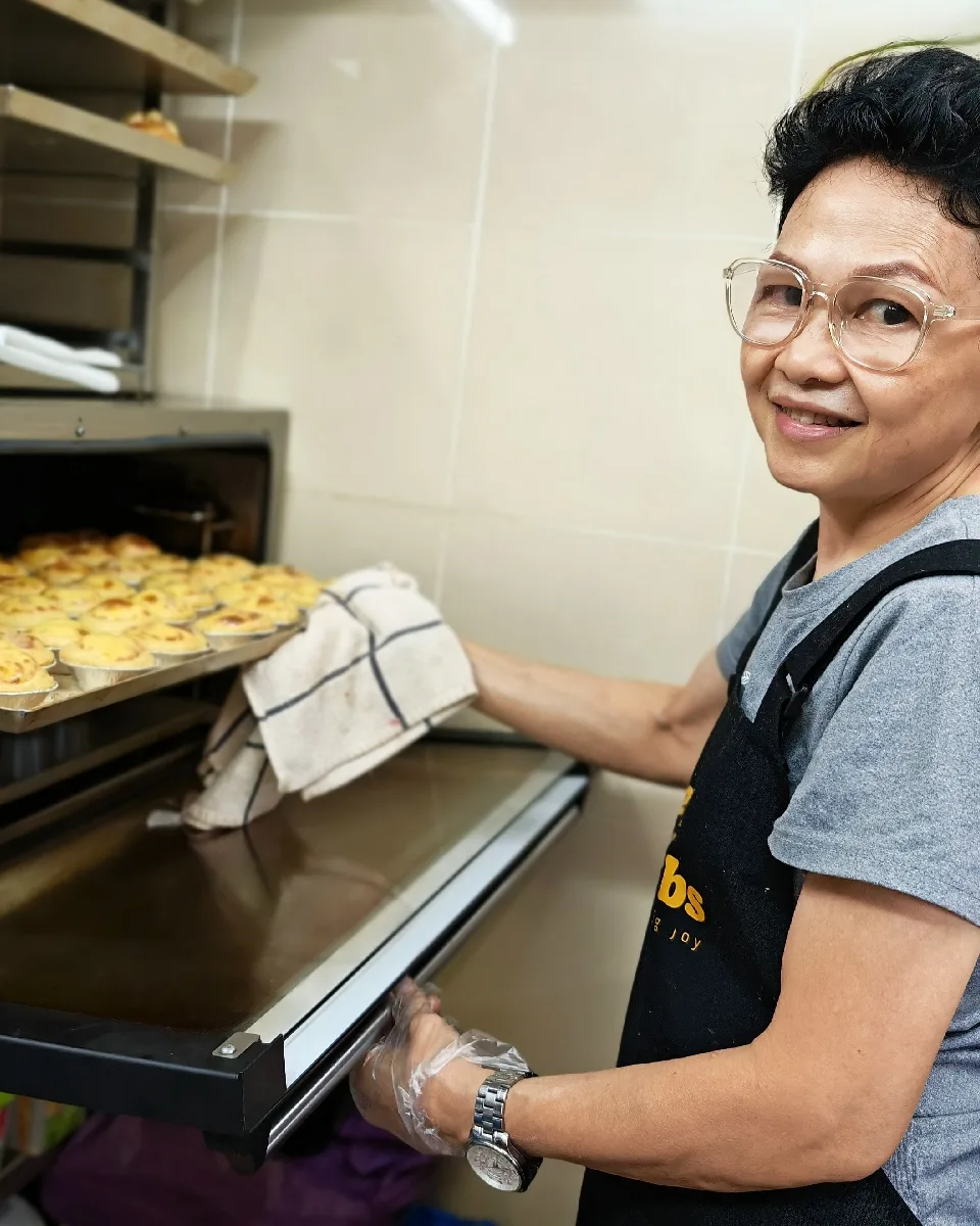 Chef Winnie Goh taking a tray of egg tarts out of the deck oven at Petite Krumbs