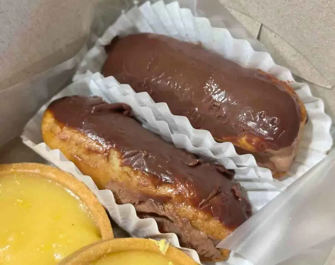 Two Valrhona chocolate eclairs from Petite Krumbs in a takeaway box