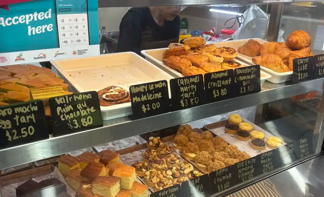 Petite Krumbs display case with hand-chalked price tags for madeleines, croissants, apple crumble and carrot cake